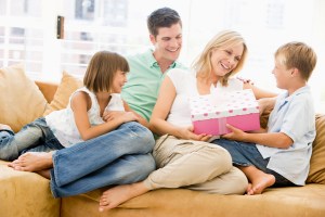 Family in living room with mother receiving gift and smiling